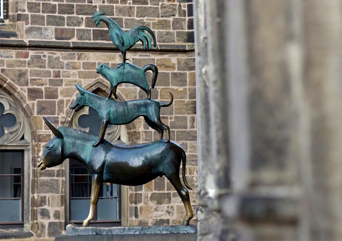 Side view of the Bremen Town Musicians. The Gothic windows of the Unser Lieben Frauen Church can be seen in the background.