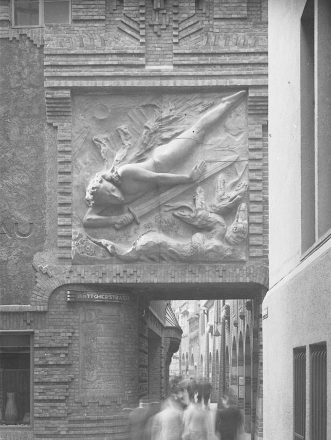 The historical photograph shows the light bringer shows the entrance of Böttcherstraße. People can be seen in the background.