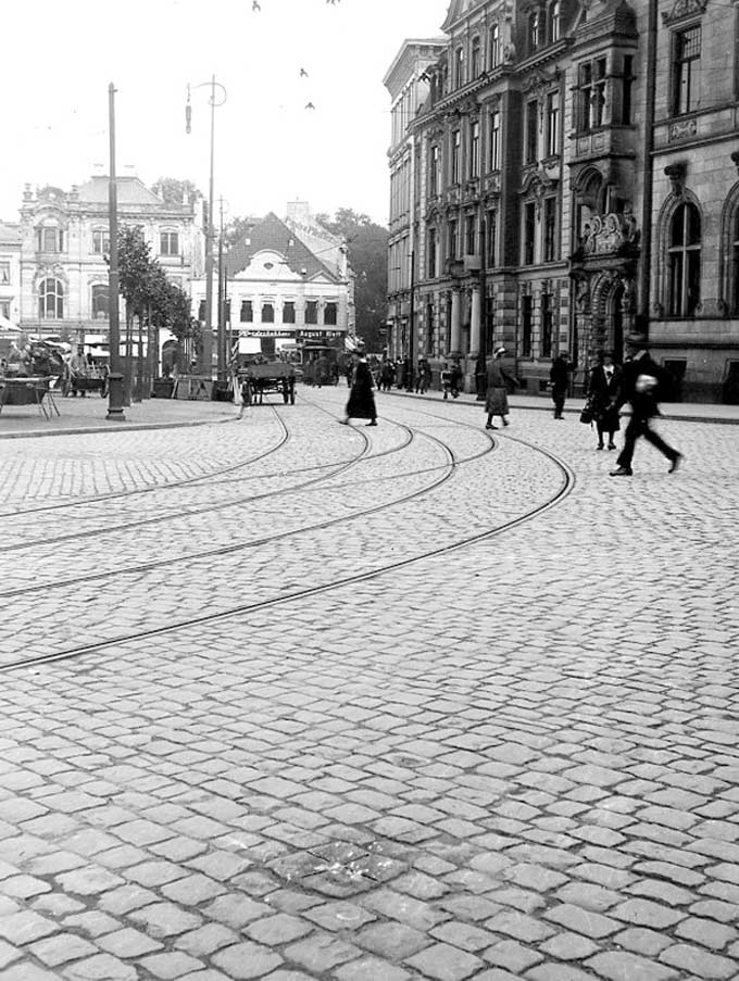 Historische Ansicht des Spucksteins. Im Hintergrund sind Straßenbahnweichen und Passanten zu sehen. Der Blick ist auf den Domshof gerichtet.